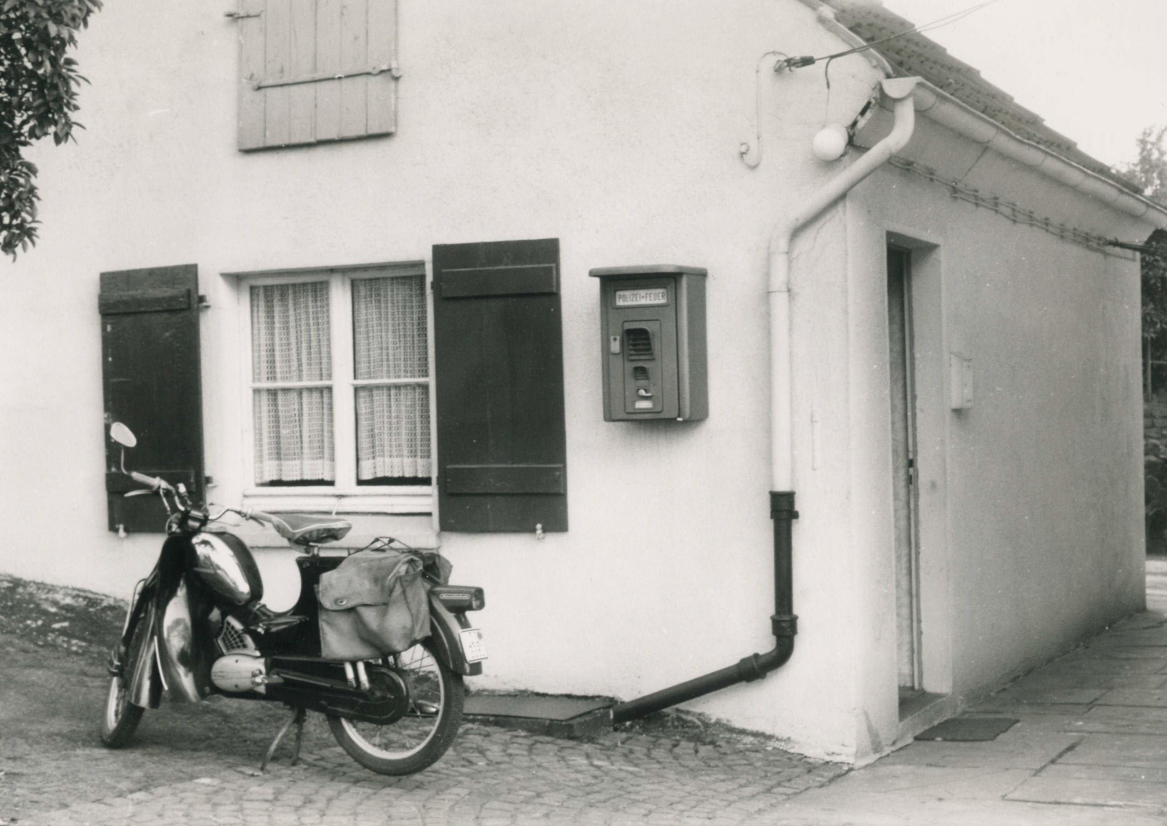 Polizeiposten Kirchhörde schwarz-weiß Außenansicht mit Motorrad vor dem Haus