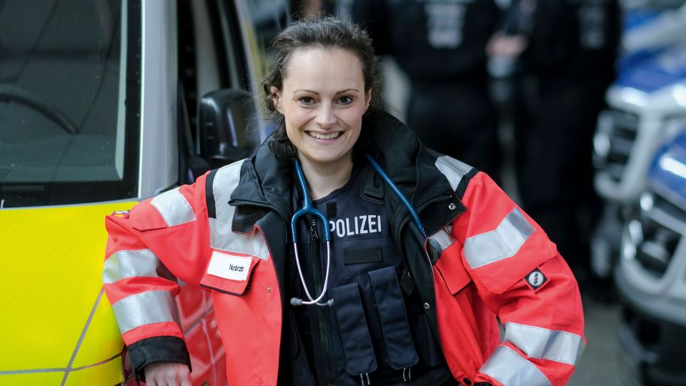 Ein blaues Stethoskop baumelt über der Polizeiweste: Die Aufgaben draußen vor Ort sind oft gefährlicher als der Klinikalltag.