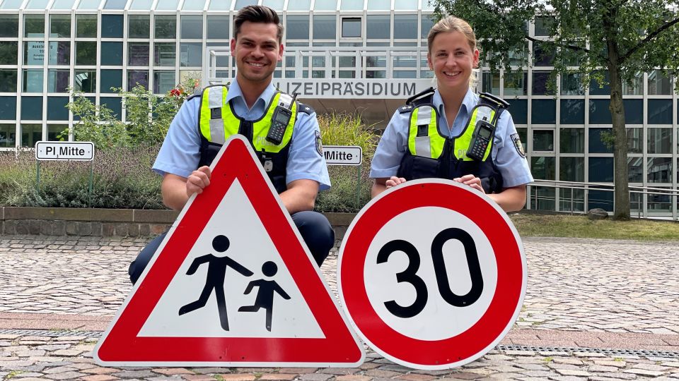 Ein Polizist und eine Polizistin werben vor dem Präsidium in Dortmund für Achtsamkeit im Straßenverkehr.